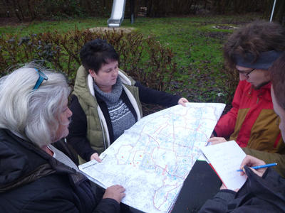 Vier Personen halten und betrachten gemeinsam einen Stadtplan.