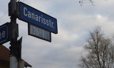 Ein Straßenschild der Canarisstraße. Im Hintergrund:Der Horizont und ein Baum.