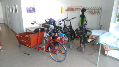 Verschiedene Fahrräder (darunter ein Lastenfahrrad und ein Fahrrad mit Schutzwimpel) parken im Tagungsraum