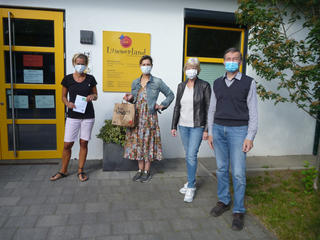 Vier Personen mit Mundschutz stehen vor dem Eingang der Kita Lummerland.